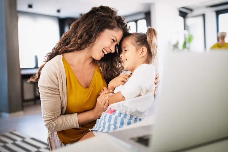 Woman laughs with a child, sits in a cozy living room