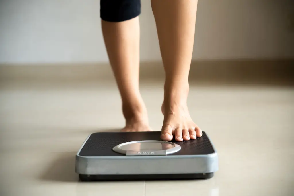 Woman with one foot on the scales, continual improvement process